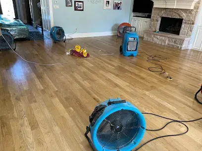 Air movers and a dehumidifier drying a hardwood living room floor in Forest Hills, TN