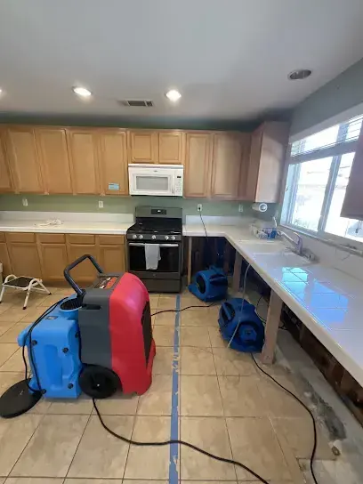Dehumidifier and air movers lined up on a kitchen tile floor in Forest Hills, TN