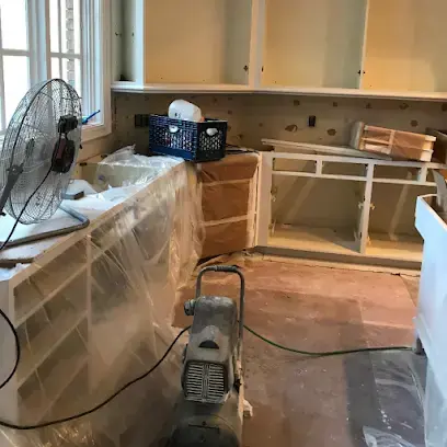Kitchen cabinets covered in plastic while a fan dries the room in Forest Hills, TN