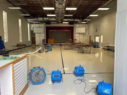 Air movers drying the floor of a large commercial hall in Brentwood, TN