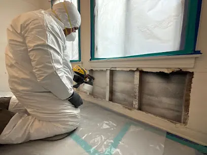 Technician in protective gear working at an opened wall under containment in Brentwood, TN